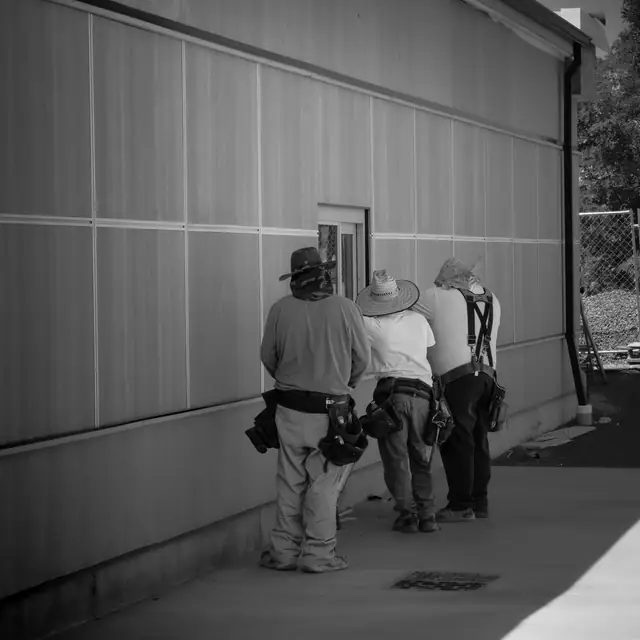 J&V Builders crew in tool belts checking a window on a commercial wall