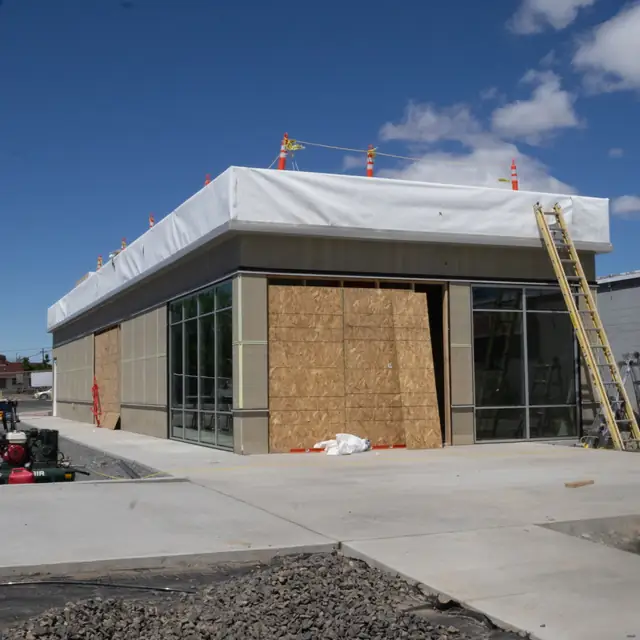 Commercial building in progress by J&V Builders, with plywood over the storefront openings and the parapet wrapped